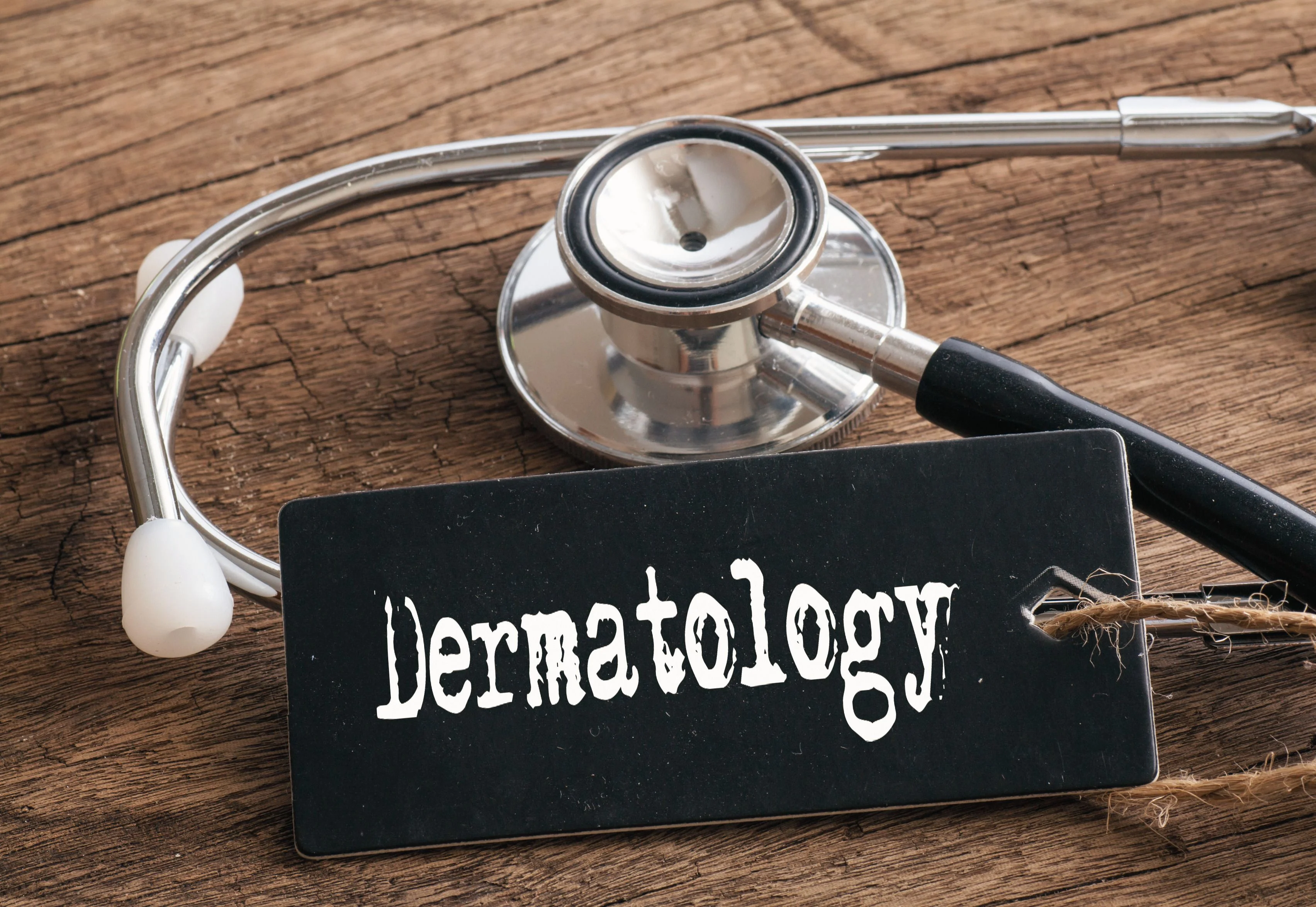 Tabla de madera con un cartel de dermatologia y un fonendo