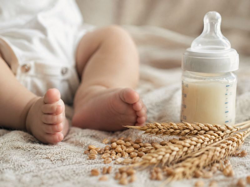 I piedini di un neonato, un biberon e delle spighe di grano