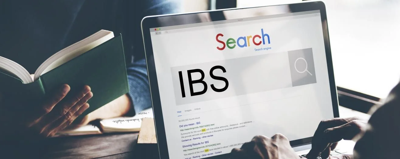 Hands typing on a laptop displaying a search engine with 'IBS' in large text