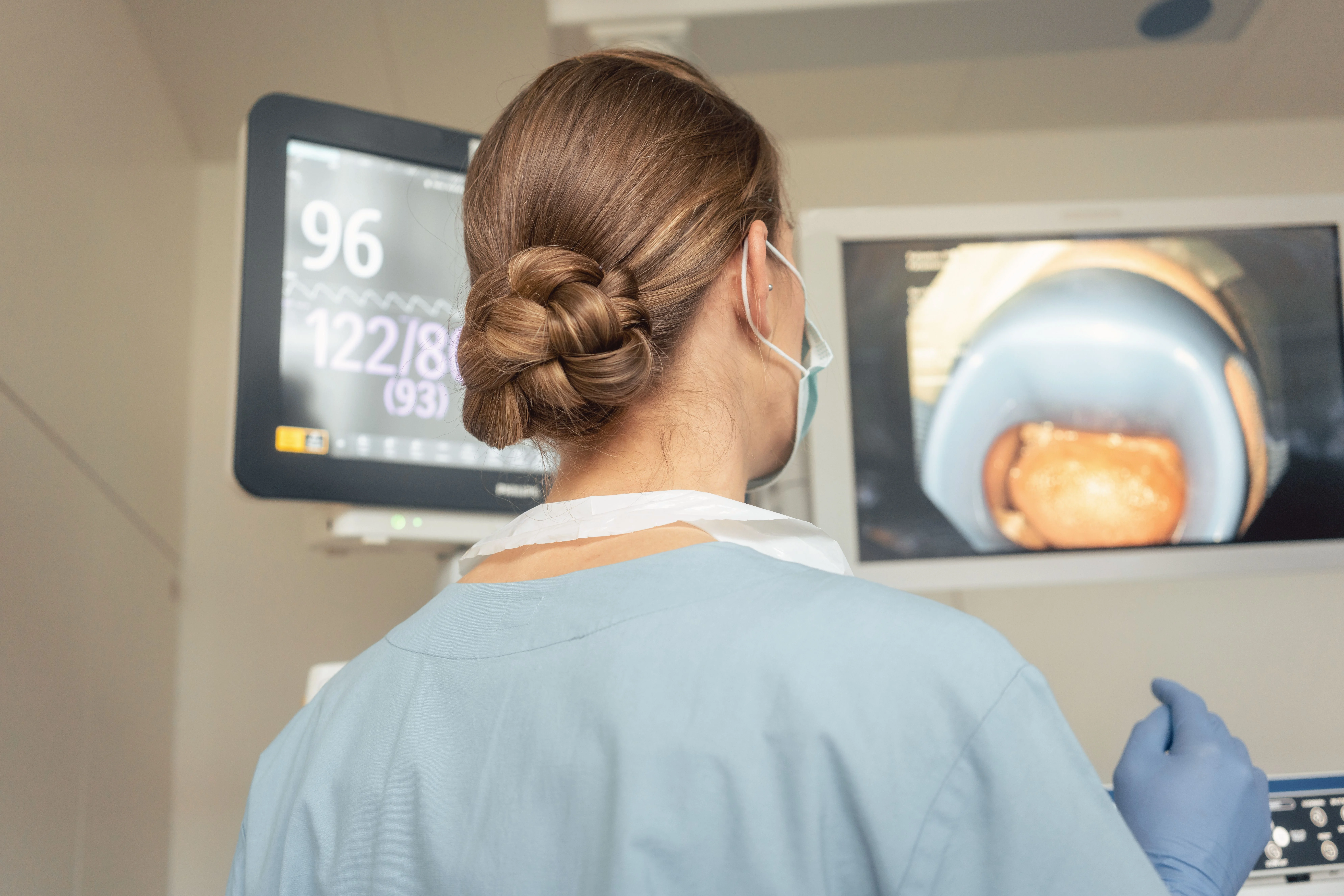 Un profesional de la salud con uniforme observa una pantalla que muestra imágenes médicas y signos vitales