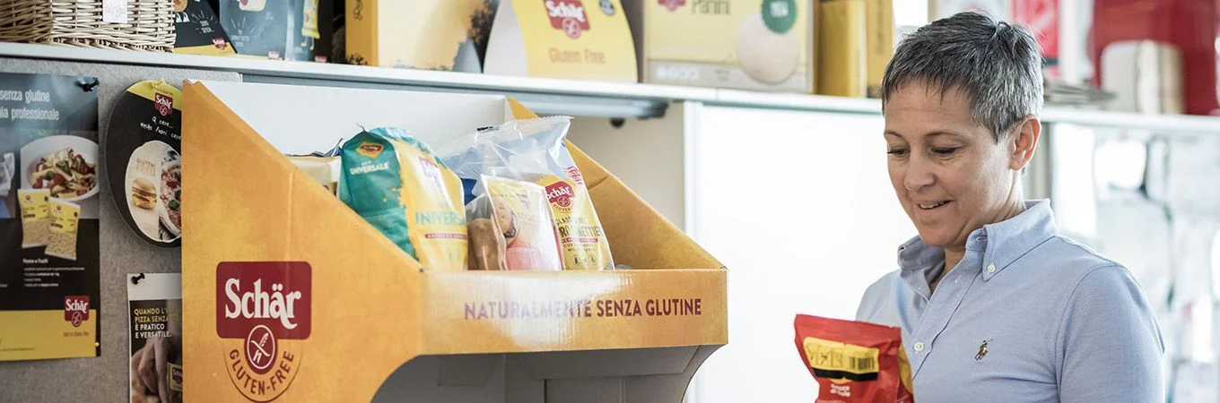 Una donna esamina prodotti senza glutine da un'esposizione in un ambiente luminoso