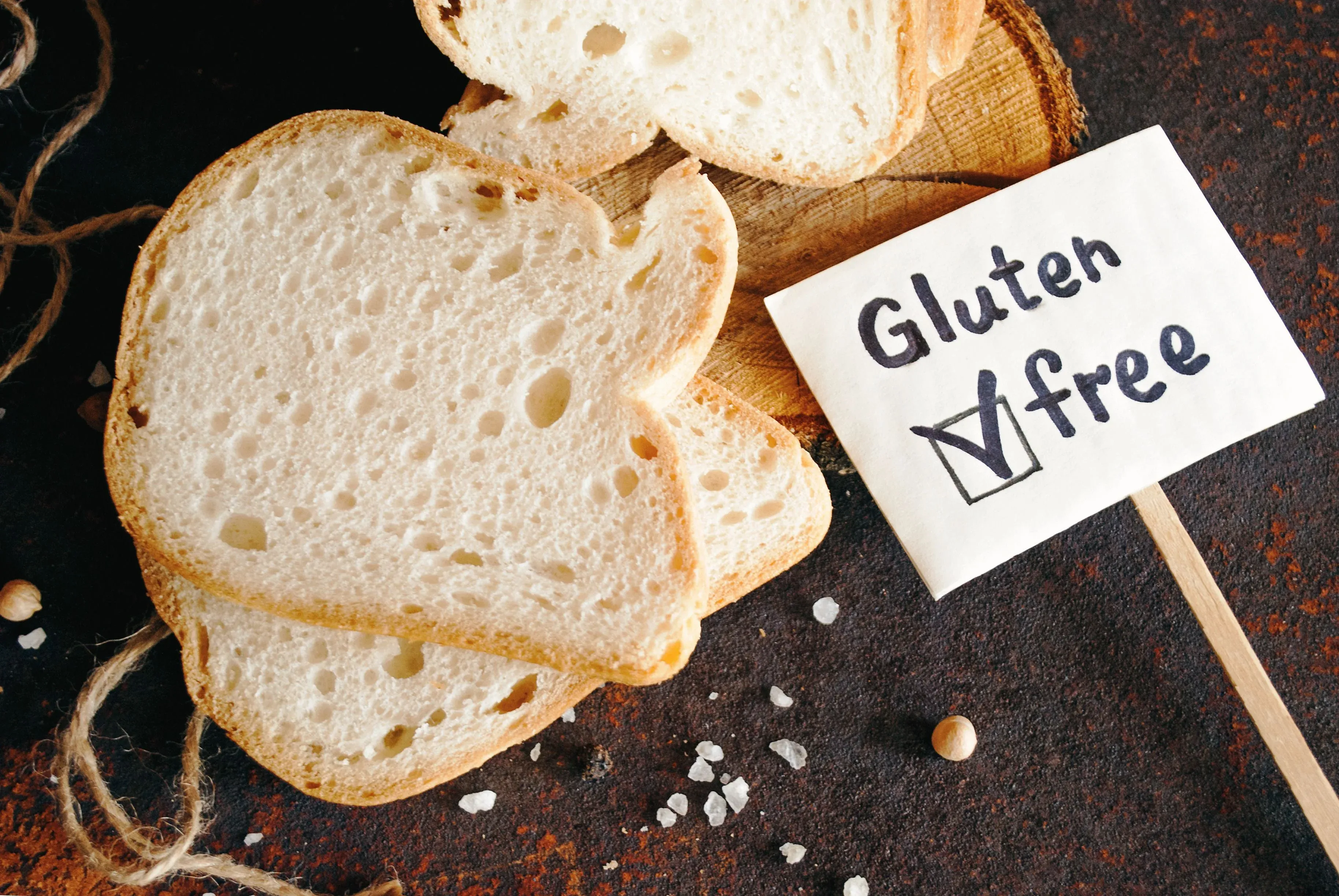 Pan sin gluten en rebanadas sobre una tabla de madera con un letrero indicando que es libre de gluten