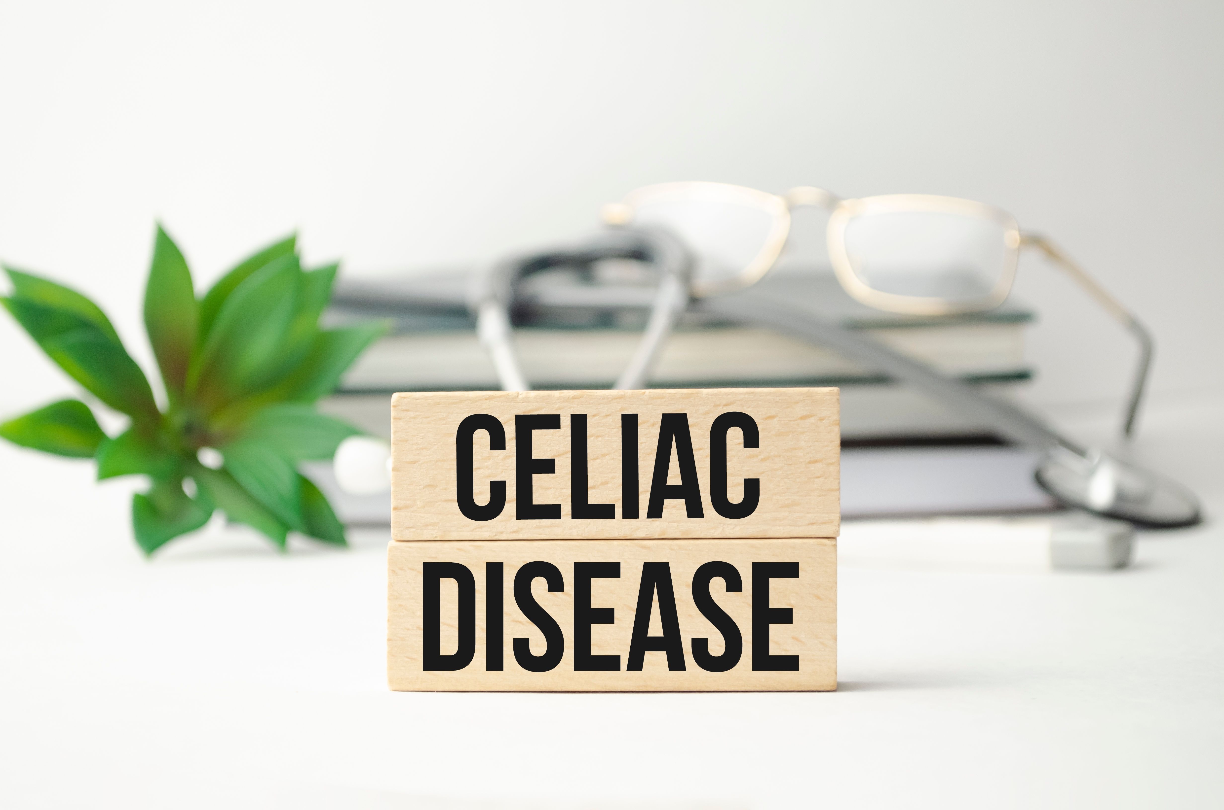 Blocks labeled "CELIAC DISEASE" with a stethoscope, glasses, and a plant in a clean, bright setting