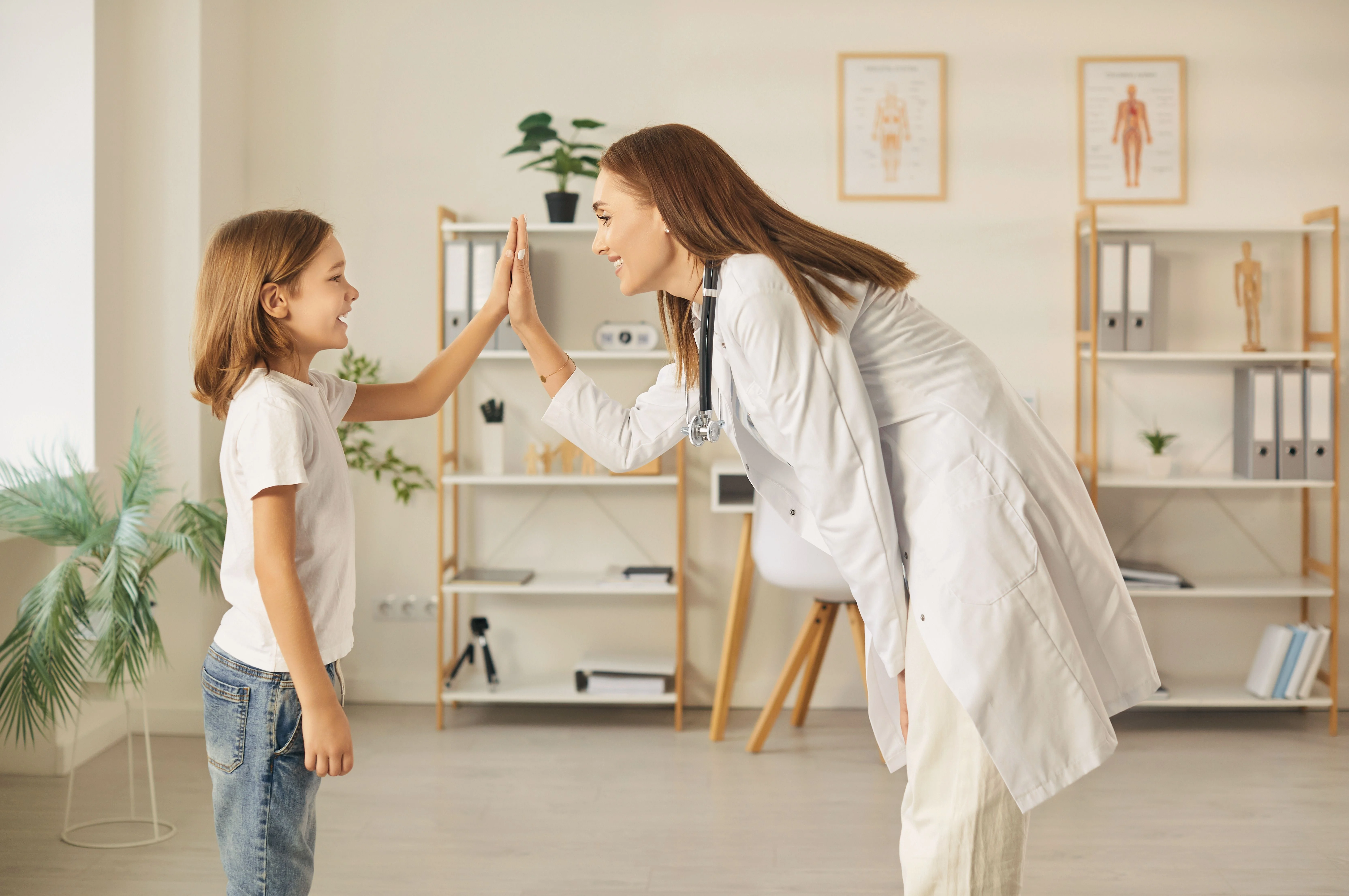 Una médica sonriente con bata blanca y un niño alegre