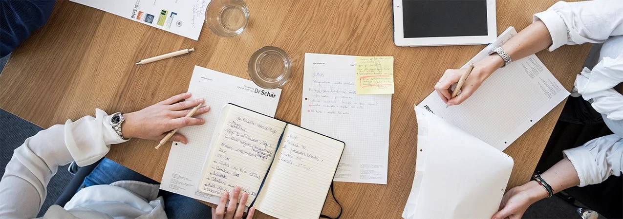 Ein Konferenztisch mit Notizbüchern, Notizen und Tablets, was Zusammenarbeit und Brainstorming anzeigt