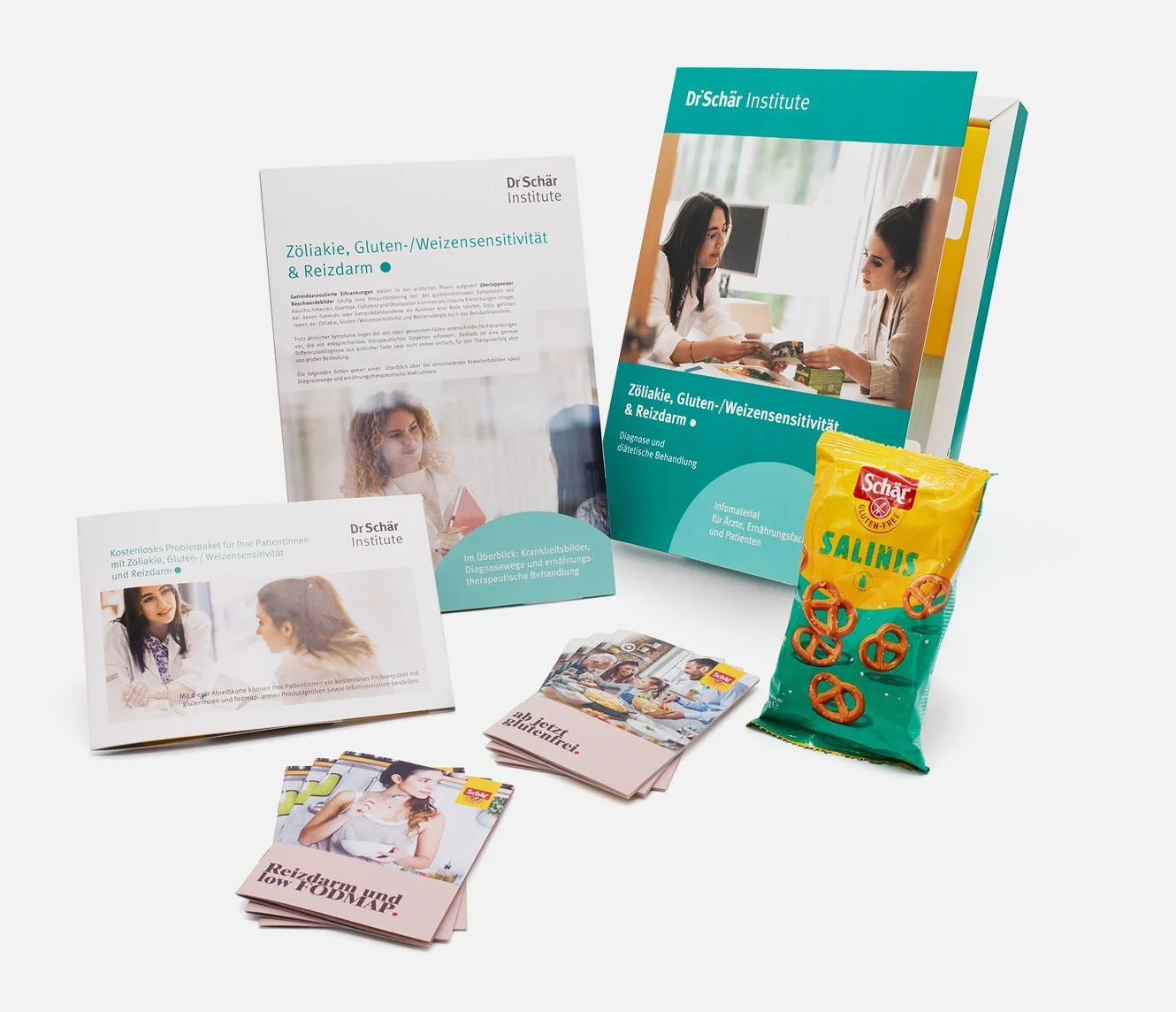 Verschiedene Informationsbroschüren und eine Snackpackung des Dr. Schär Instituts zu Glutenunverträglichkeit und Zöliakie